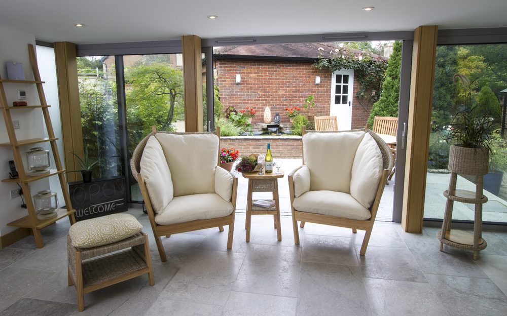 Two Semarang armchairs and a side table in a garden room opening onto a patio