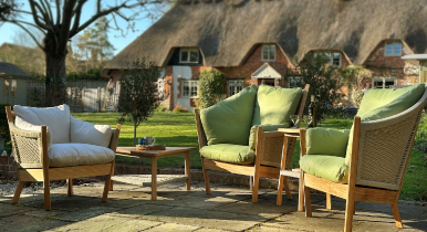 Semarang Outdoor furniture arranged on a patio in front of a thatched roof English country cottage